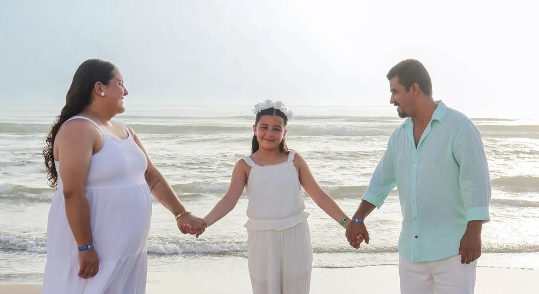 Familia tomada de la mano en la playa
